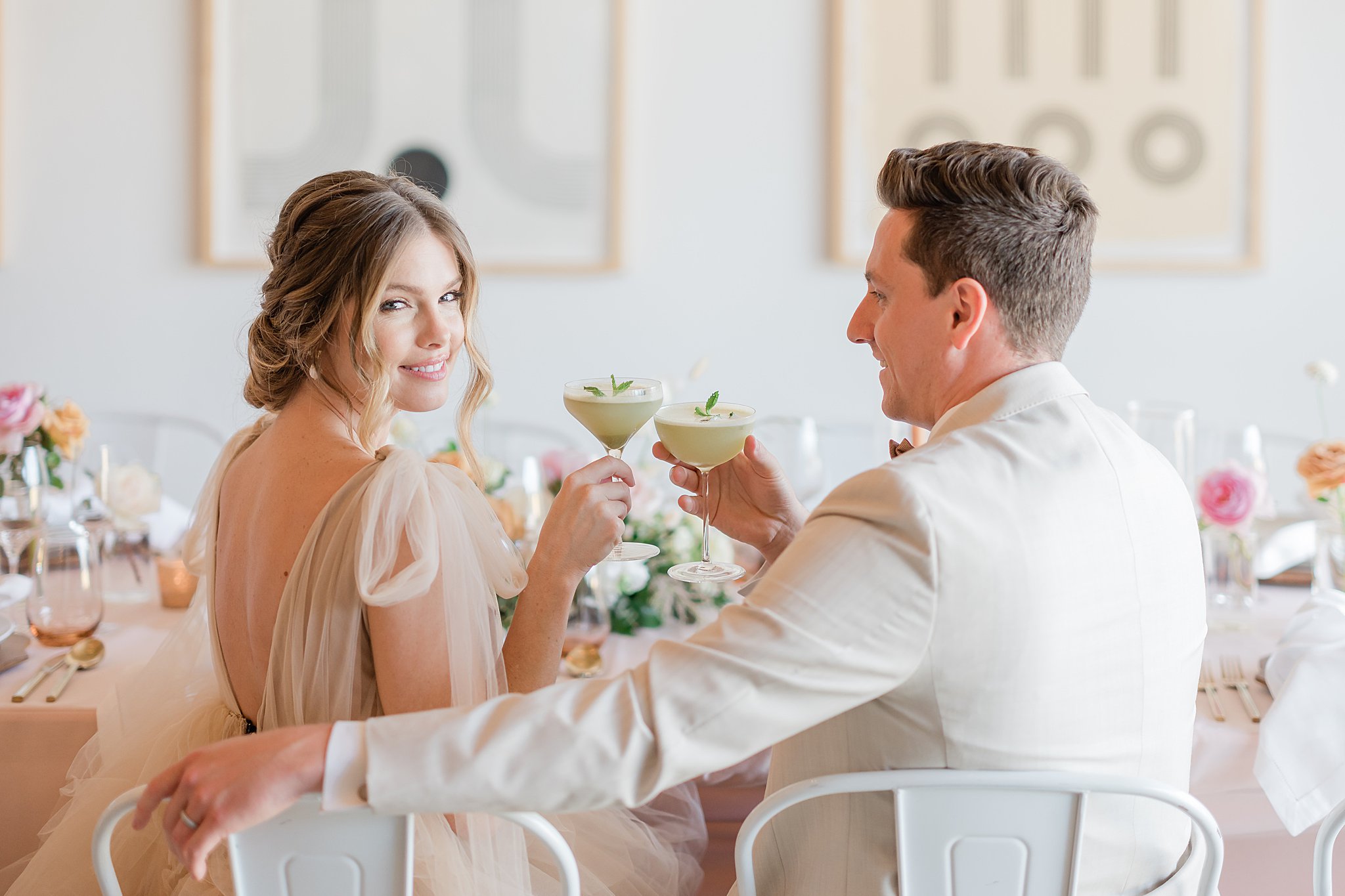 bride and groom clink glasses at table