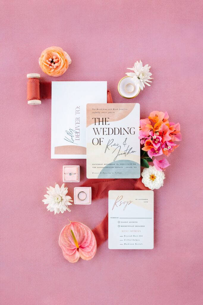 Pink wedding flatlay with colorful flowers and wedding invitation suite