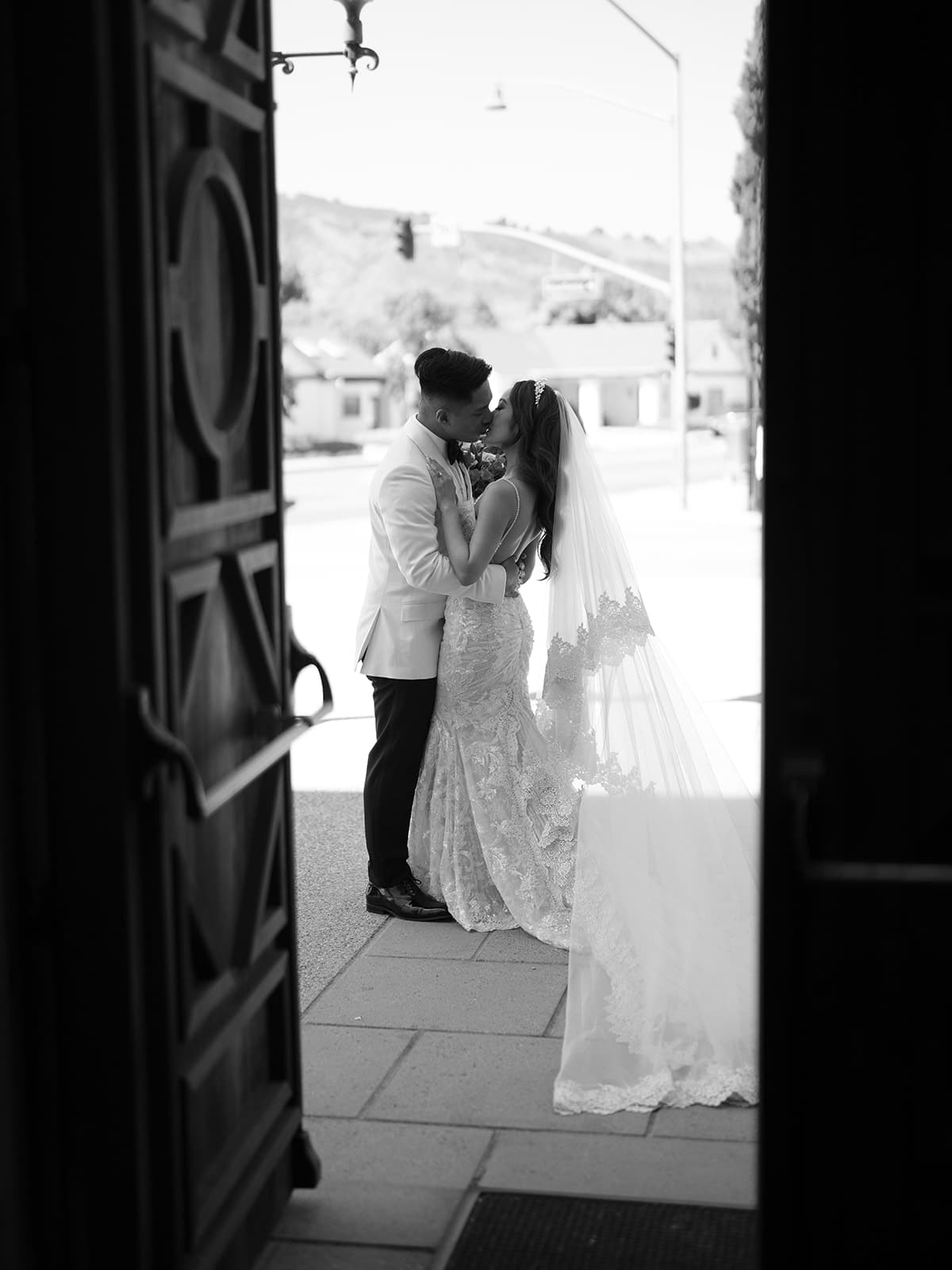 Black and white photo of a bride and groom taken through a doorway at Casa Romantica