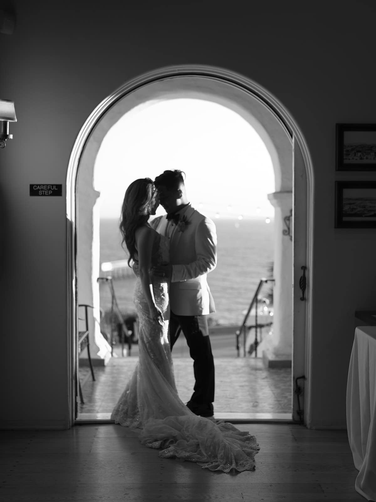 Black and white photo of a bride and groom kissing under an arch at Casa Romantica