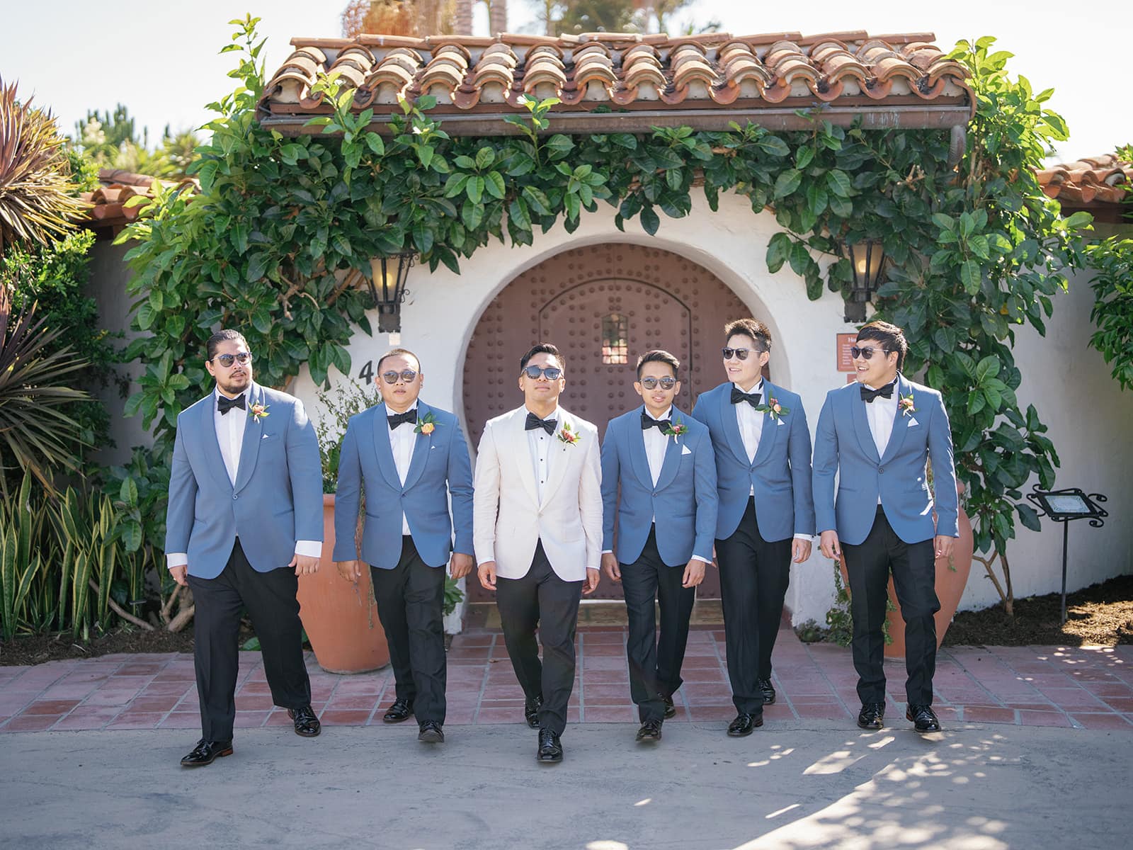 The groomsmen with sunglasses standing side by side in front of a San Clemente wedding venue