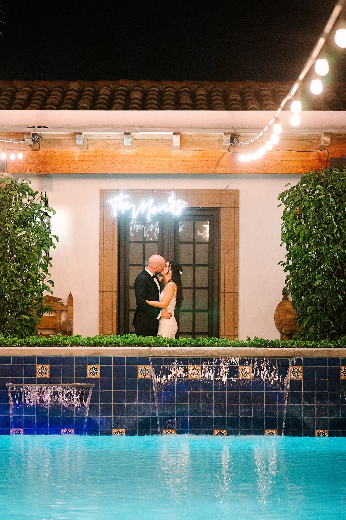 Romi and Jonathan kissing under a neon sign at Bougainvillea estate